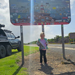 Child with south australian travel ournal in front of state boarder sign