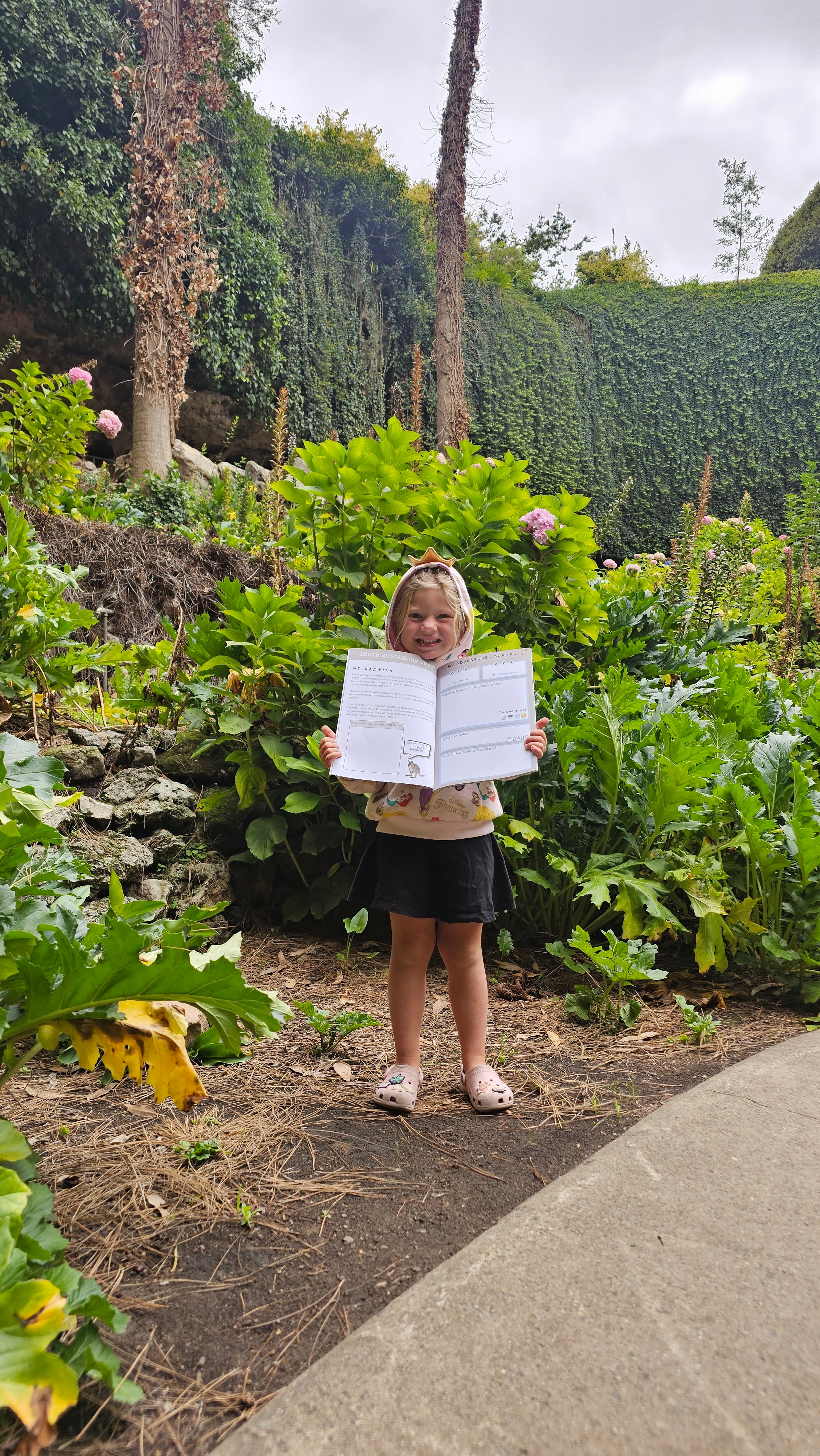 child holding up south australian travel journal at a sink hole