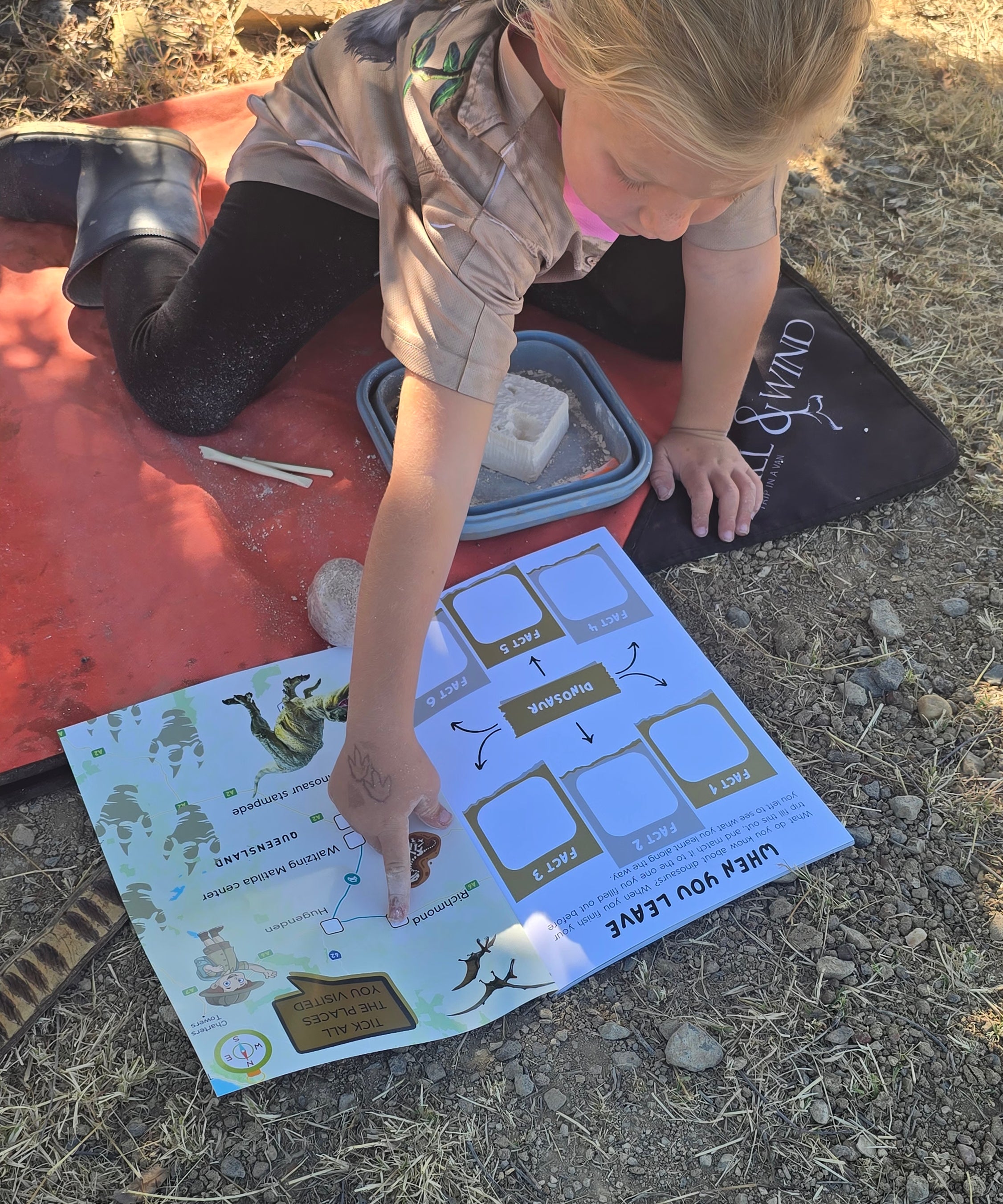 Child playing with a dinosaur travel journal outdoors on a sunny day