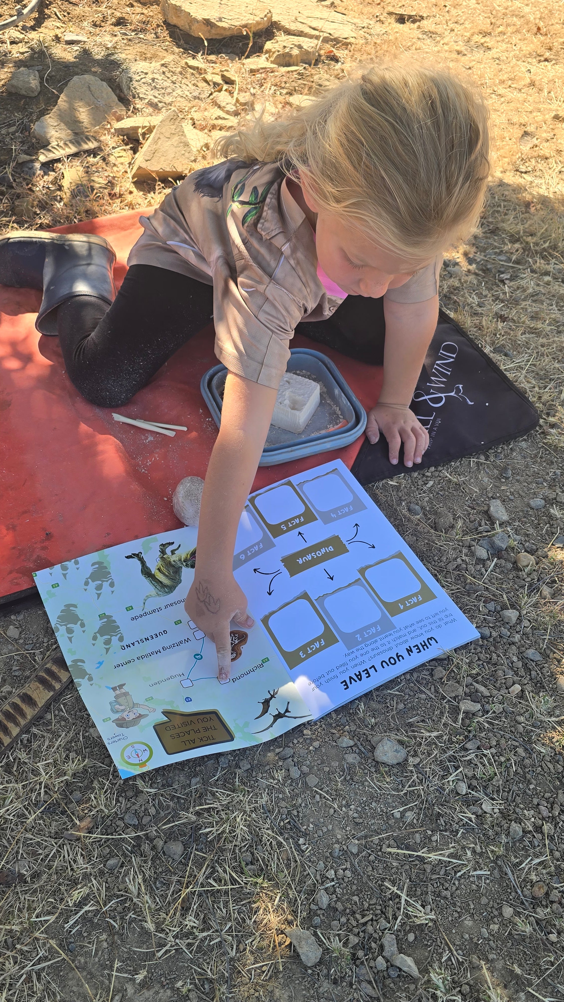 Child playing with a dinosaur travel journal outdoors on a sunny day