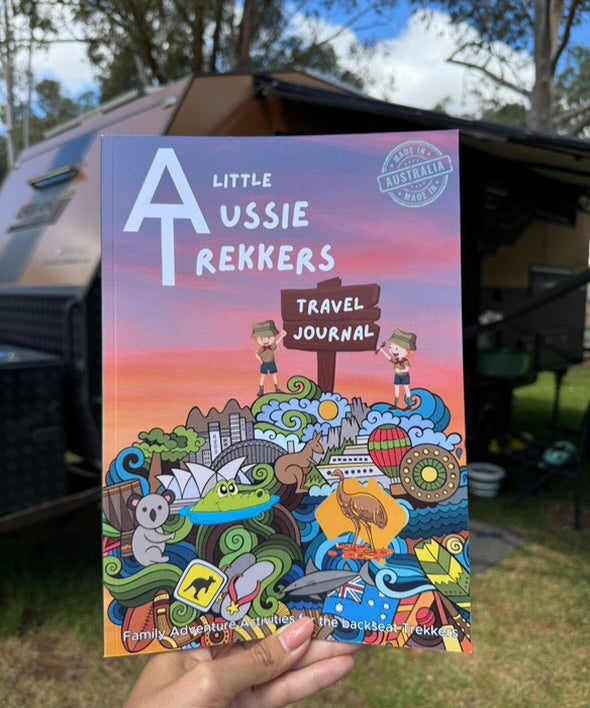 A colorful travel journal titled 'Kids Australian Travel Journal' being held in front of a camping backdrop.