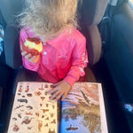 Child in car seat with stickers in an australian travel journal titled the kimberley