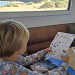 Child in pajamas reading a south australian travel journal couch with a scenic view outside