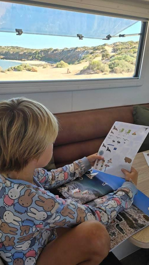 Child in pajamas reading a south australian travel journal couch with a scenic view outside