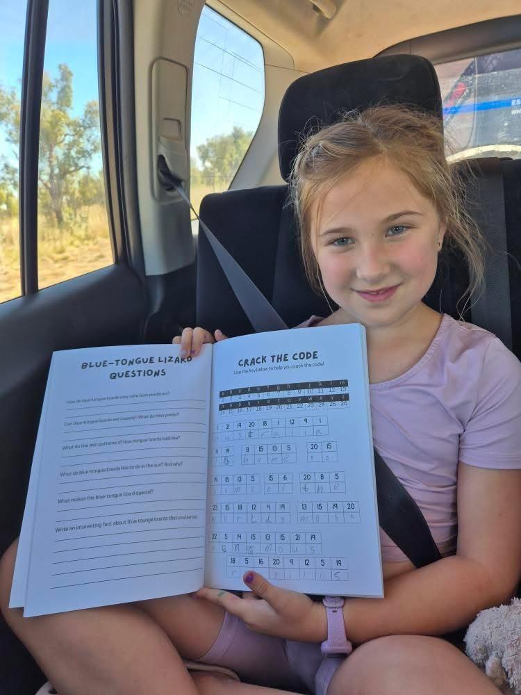 Young girl sitting in a car holding an australian animal book with questions and answers.