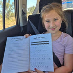 Young girl sitting in a car holding an australian animal book with questions and answers.