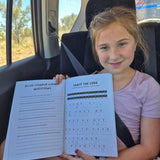 Young girl sitting in a car holding an australian animal book with questions and answers.