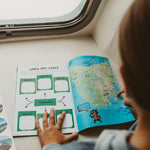 Child reading a journal with a map on a train or vehicle seat
