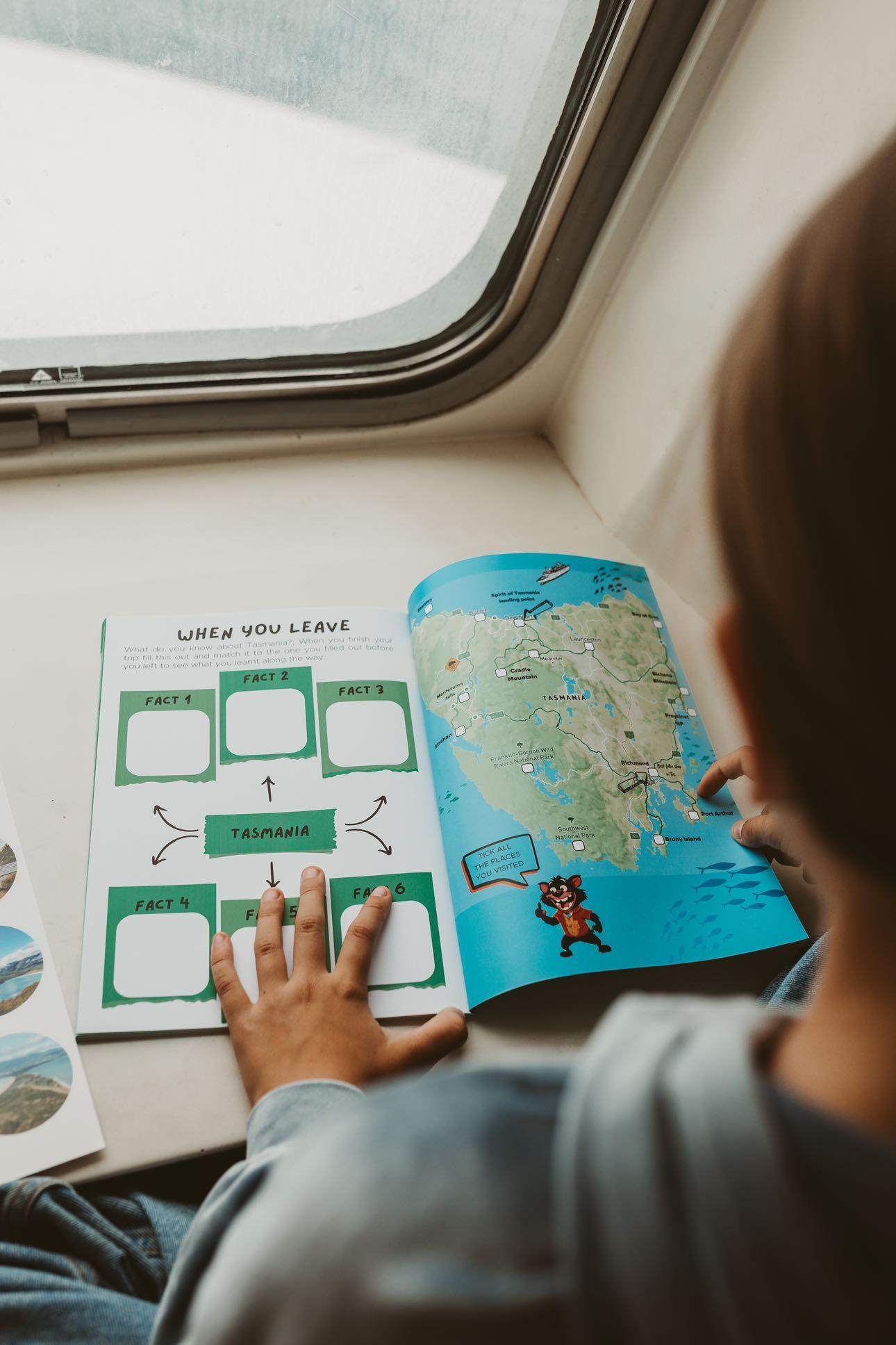 Child reading a journal with a map on a train or vehicle seat