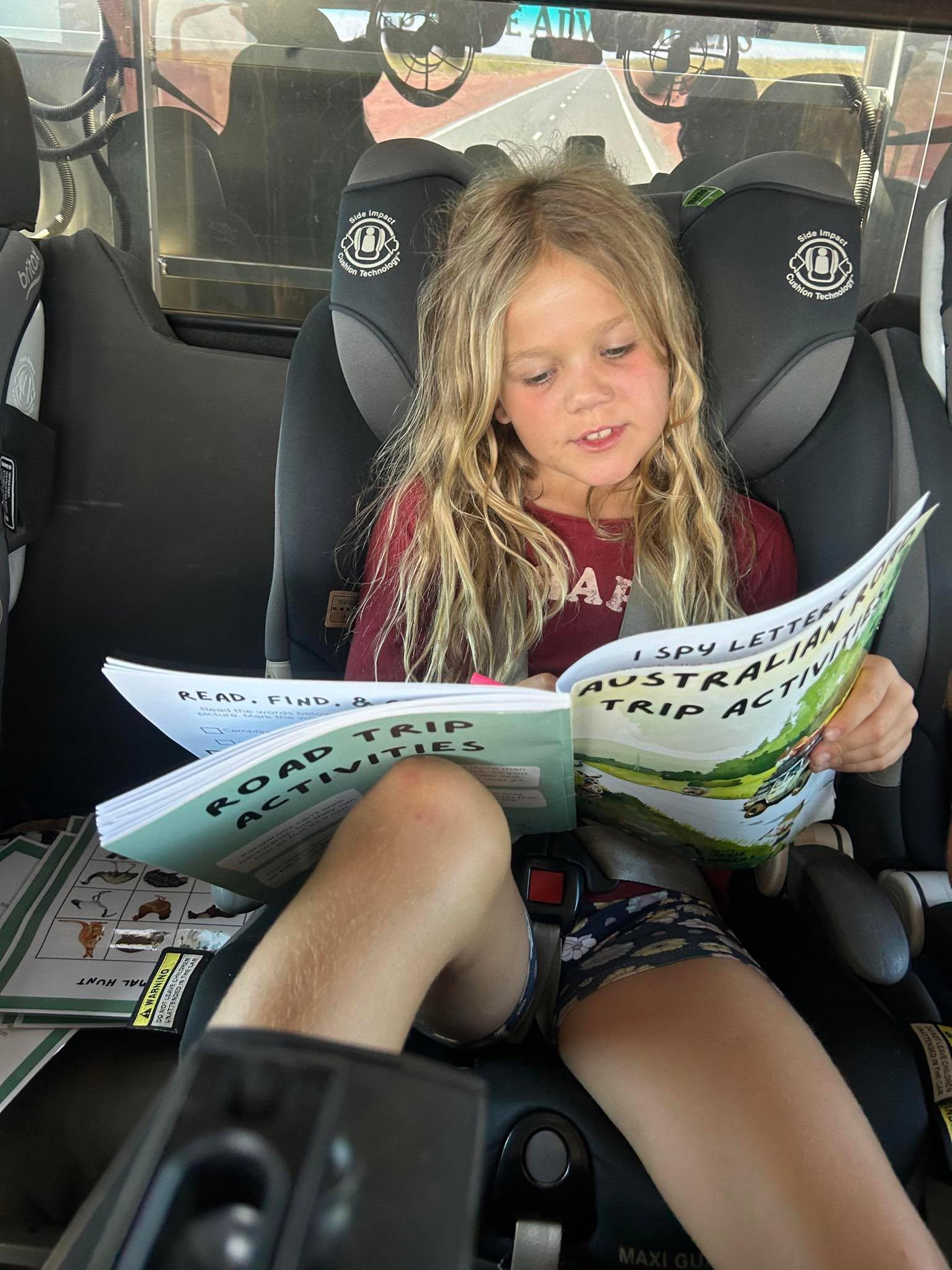 Child  completing an australian road trip activity in a car seat with road trip activities.