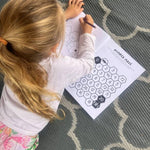 Child coloring a number maze on a  australian activity book with a crayon on a patterned rug.