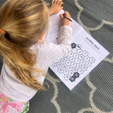 Child coloring a number maze on a  australian activity book with a crayon on a patterned rug.