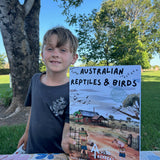 Child holding up australian reptiles and birds activity book
