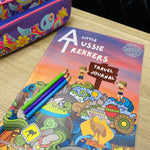 Colorful travel journal titled 'Australian Travel Journal' with pencils on a wooden surface.