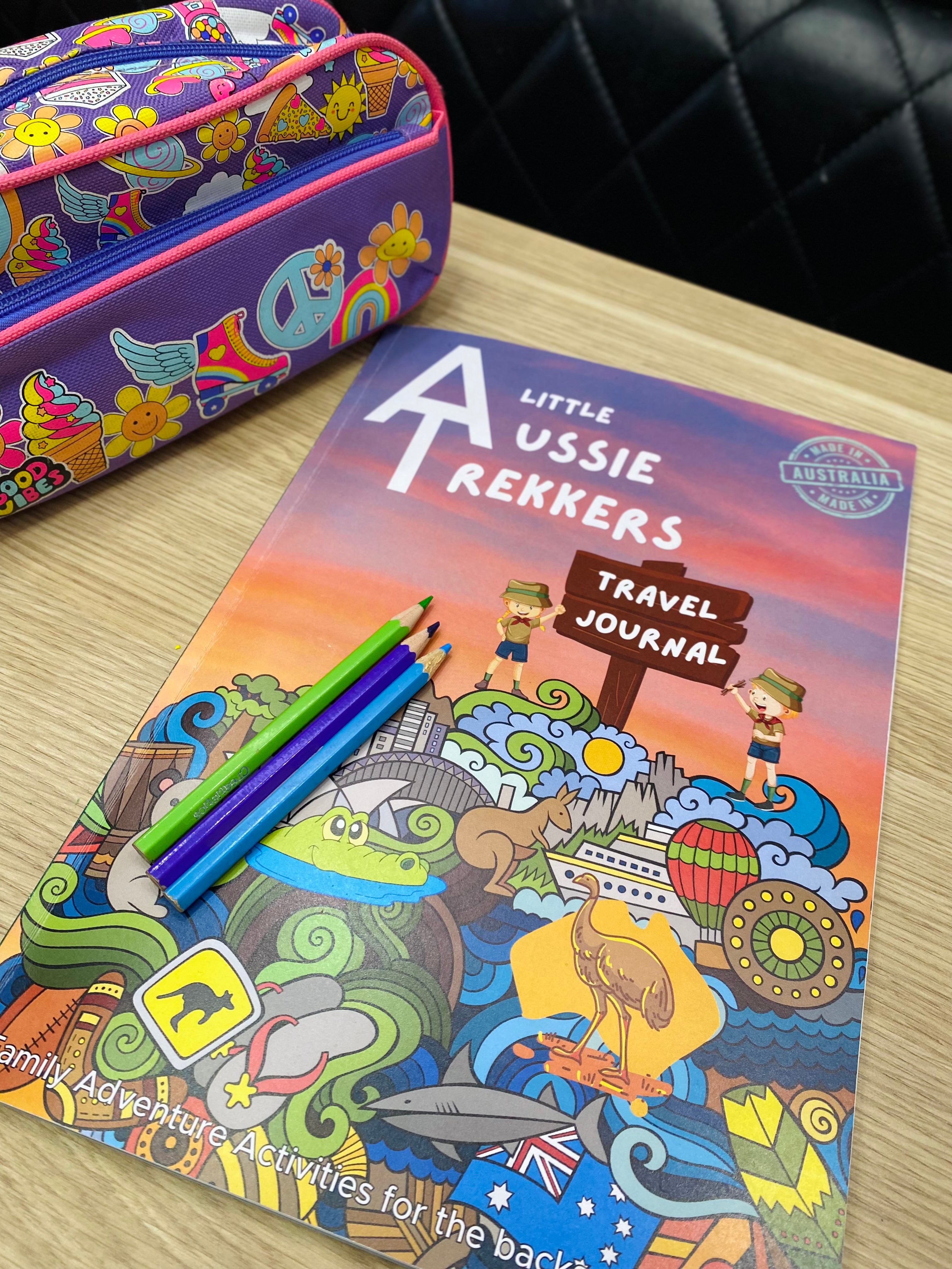 Colorful travel journal titled 'Australian Travel Journal' with pencils on a wooden surface.