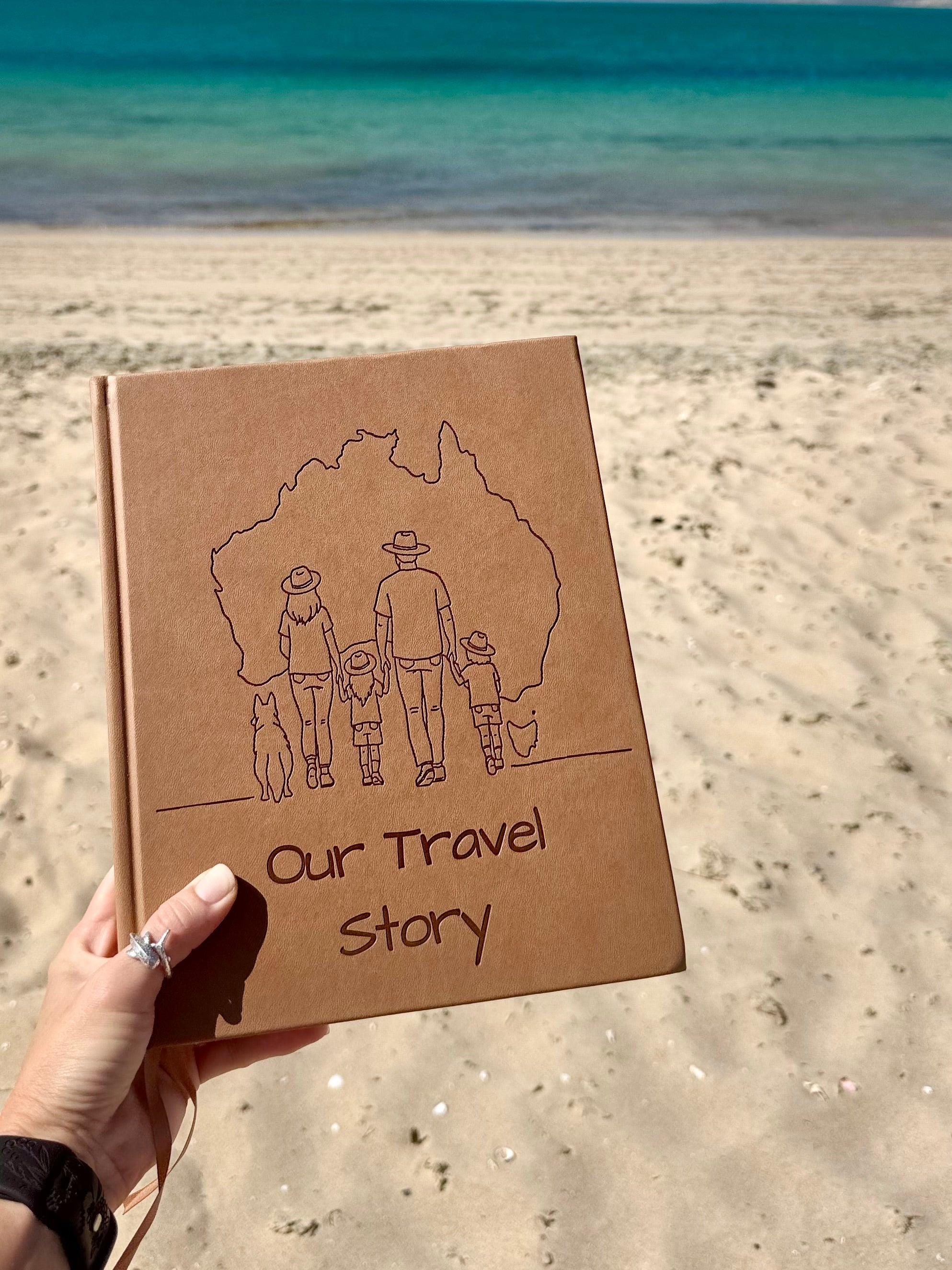 Sand coloured australian travel journal with 'Our Travel Story' text and family illustration held on a beach.