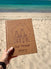 Sand coloured australian travel journal with 'Our Travel Story' text and family illustration held on a beach.