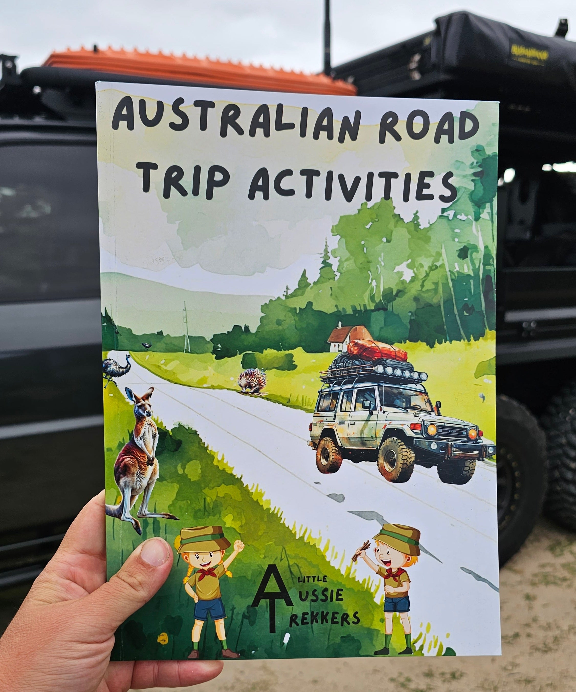 Australian Road Trip Activitys book held up in front of car